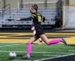 Soccer player in action wearing black and pink, mid-kick on field at Baierl Center.