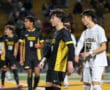 High school soccer players from rival teams during a night match. Players in focus wearing black and white jerseys.