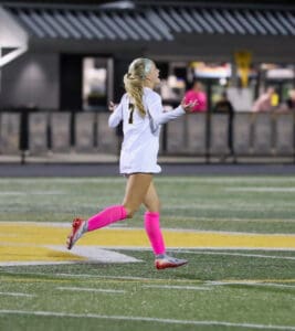 Soccer player in pink socks celebrates on the field during a night match.