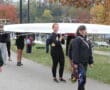 Rowing team carrying a boat on a pathway with autumn trees in the background.