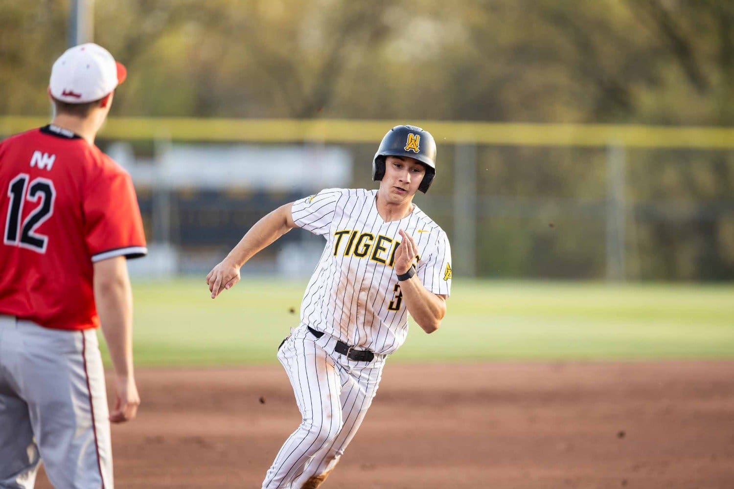 Baseball player in action, running towards base, wearing a Tigers jersey and helmet.