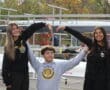 Three happy people forming the letter M with their arms at a rowing event.
