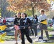 Rowing team carrying oars at a park during autumn, preparing for a practice session.