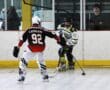 Two inline hockey players in action on the rink, one in red, number 92, and the other in white, number 43.