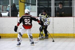 Two inline hockey players in action on the rink, one in red, number 92, and the other in white, number 43.