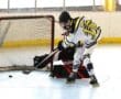 Roller hockey player attempts to score against goalie in dynamic match action.