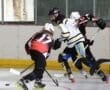 Three hockey players in action on an indoor rink, competing intensively for the puck.