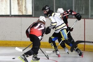 Three hockey players in action on an indoor rink, competing intensively for the puck.