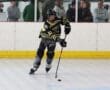 Youth inline hockey player in action, focused on puck control during a match on the rink.