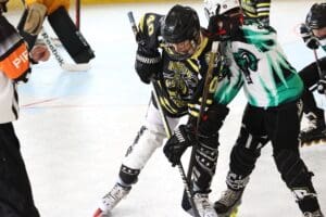 Two inline hockey players in action, battling for the puck on a rink.