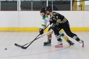Roller hockey players in action during an intense match on an indoor rink.
