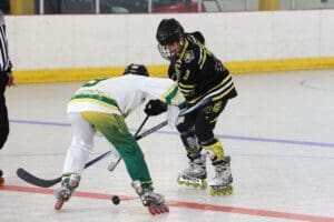 Inline hockey players face off during a competitive match in an indoor rink.