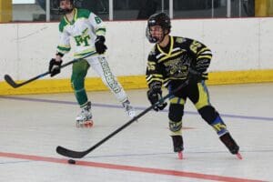 Two inline hockey players in action, focus on puck and teamwork on rink.
