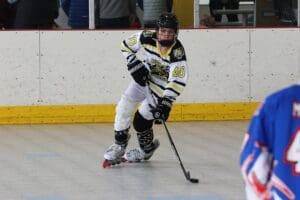 Roller hockey player in action on the rink, wearing a black and white jersey with the number 40.