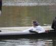 Rowing team preparing on the water with a coach's guidance on a calm lake during training.