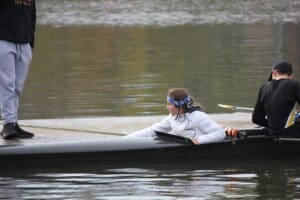 Rowing team preparing on the water with a coach's guidance on a calm lake during training.