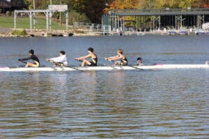 Rowers compete in a regatta at Scioto Boat Club with vibrant autumn foliage in the background.