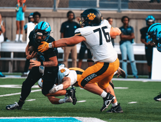 Football players in action during a game; one player tackles another on the field.