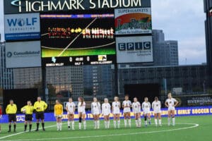 Girls' soccer team lineup at Highmark Stadium with scoreboard displaying 0-0 halftime score.