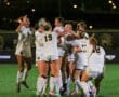 Team of female soccer players celebrating a victory at night on the field.