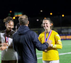Athletes receiving medals during a nighttime soccer award ceremony on the field.