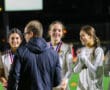 Girls' soccer team receiving medals during night ceremony on the field.