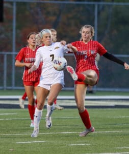 Soccer players in red and white jerseys competing for the ball on the field during a match.