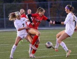 Soccer players compete for the ball during a match on a grassy field.