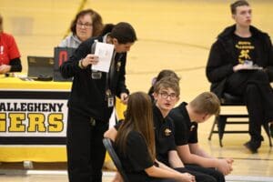 People in black attire at a sports event, discussing strategy on the bench.