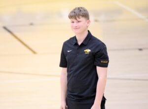 Smiling person in black BOCES polo on a gym floor, representing Special Olympics Unified Sports.