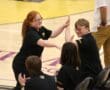 Group of people giving high-fives at a sports arena, wearing matching black shirts, celebrating success.