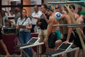 Swimming competition preparation with coaches and athletes at the poolside.