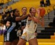 Two high school girls basketball players in action during a game, focusing on scoring and defense.