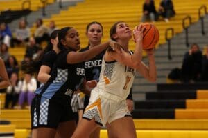 Two high school girls basketball players in action during a game, focusing on scoring and defense.
