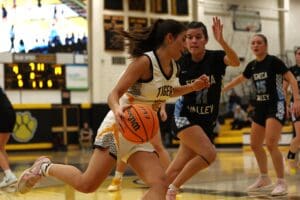 Basketball player drives past defender in competitive high school game.