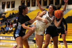 Girls' high school basketball game, intense action under the basket, players from Tigers and Seneca Valley competing.
