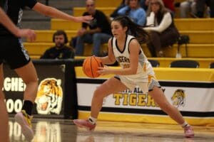 Basketball player dribbles past a defender during a high school game at Tigers arena.