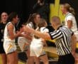Referee points during an intense women's basketball game as players react passionately on the court.