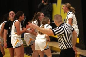 Referee points during an intense women's basketball game as players react passionately on the court.