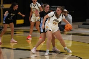 Girls' basketball game action, player in white dribbles while defended, showcasing agility and teamwork on the court.
