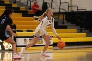Female basketball player dribbling past opponent in a gym. Action-packed sports scene.