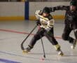 Inline hockey players in action on the rink, wearing helmets and skates, competing for the puck.