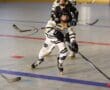 Youth inline hockey players compete with intensity on the rink, chasing the puck during a fast-paced game.
