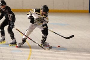 Inline hockey players in intense action on rink, focusing on puck control and teamwork.