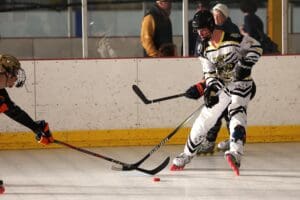 Hockey players in action on the rink, engaging in a competitive match with bright uniforms and gear.