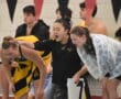 Excited swim team cheering poolside during a competitive swim meet indoors.