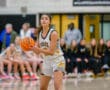 Female basketball player from the Tigers team prepares to make a pass during a game in a gymnasium.