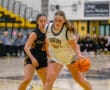 Two female high school basketball players competing on the court during a game.