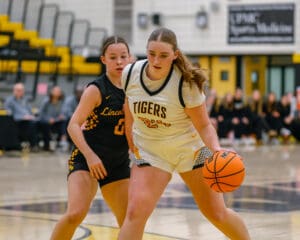 Two female high school basketball players competing on the court during a game.