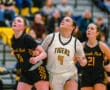 High school girls basketball game action, players in intense focus during a play.